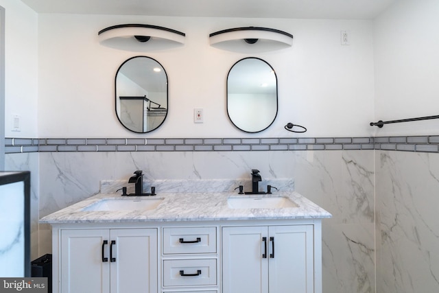 bathroom featuring tile walls, a wainscoted wall, double vanity, and a sink