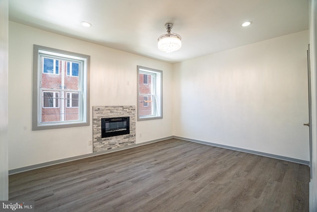 unfurnished living room with baseboards, a fireplace, recessed lighting, and wood finished floors