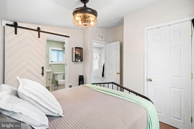 carpeted bedroom with a barn door and connected bathroom
