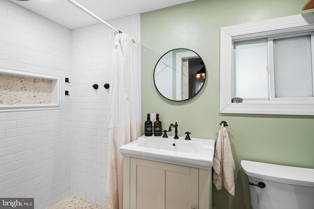 full bath with vanity, a tile shower, and toilet