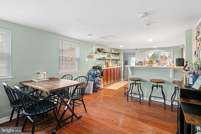 dining room featuring healthy amount of natural light, wood finished floors, a dry bar, and recessed lighting