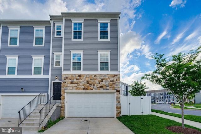 5992 Passend Dr, Frederick, MD 21703 - townhome / multi-family property featuring stone siding, an attached garage, driveway, a gate, and fence