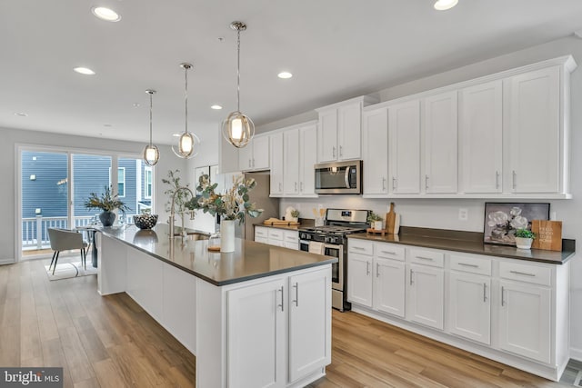 5992 Passend Dr, Frederick, MD 21703 - kitchen featuring appliances with stainless steel finishes, a sink, dark countertops, light wood-type flooring, and white cabinets