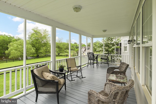 sunroom featuring view of wooded area