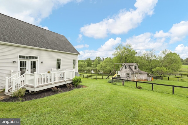 view of yard with a deck with water view, an outbuilding, a barn, and french doors