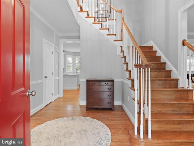 foyer entrance with wood finished floors, stairs, ornamental molding, and baseboards