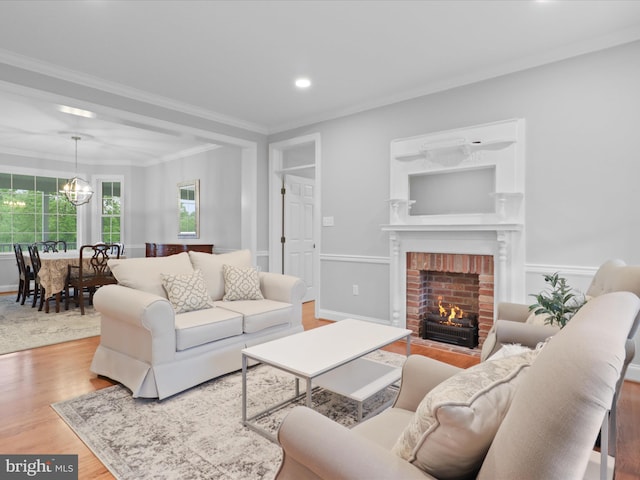 living area featuring wood finished floors, a fireplace, crown molding, a chandelier, and recessed lighting