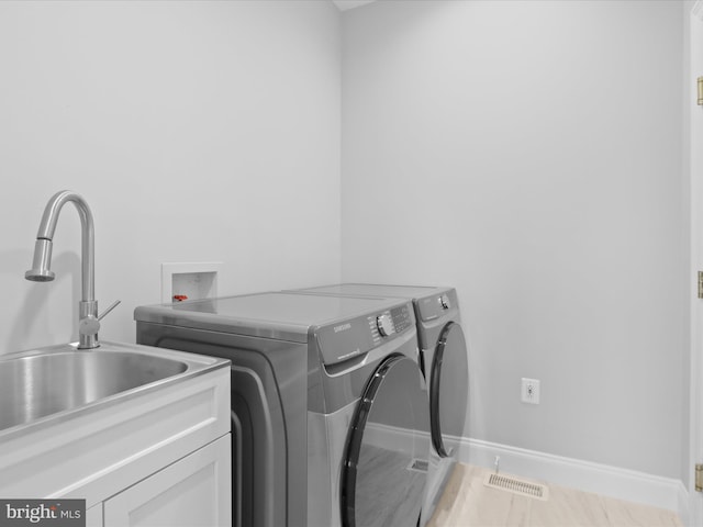 laundry area featuring washer and clothes dryer, cabinet space, and baseboards