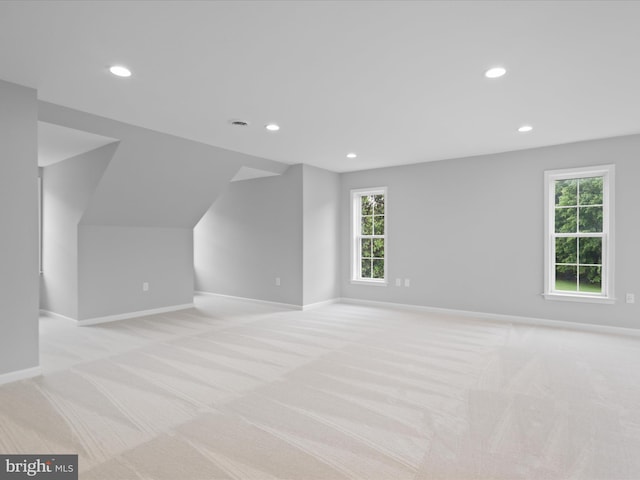 additional living space with light colored carpet, recessed lighting, baseboards, and plenty of natural light