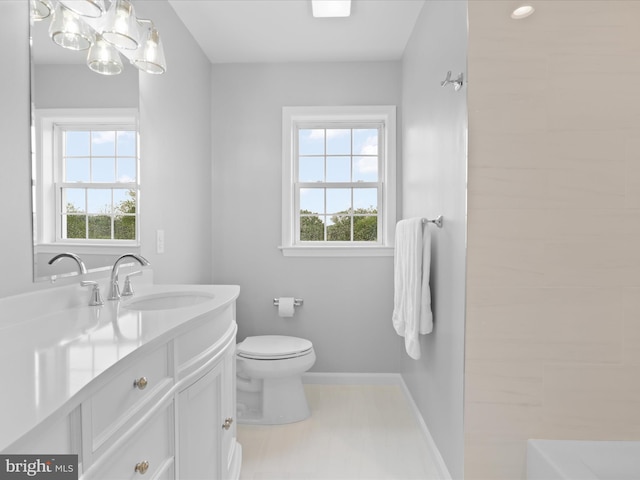 full bath featuring plenty of natural light, toilet, vanity, and baseboards