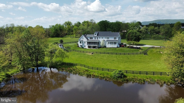 view of rural area with a nearby body of water, a pastoral area, and a heavily wooded area