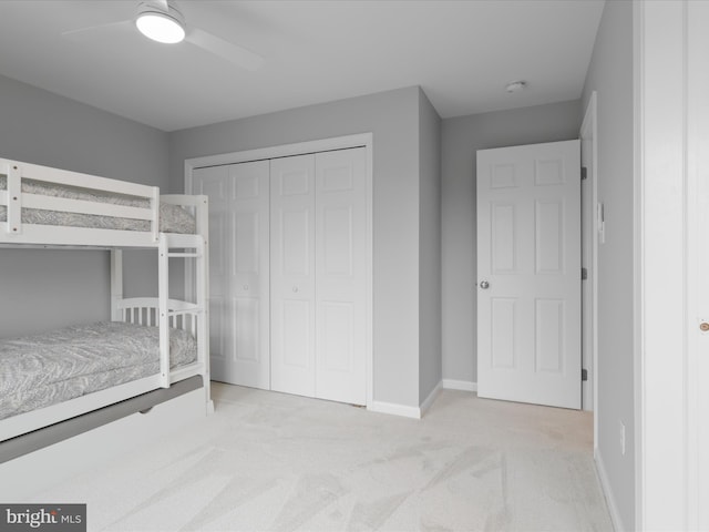 unfurnished bedroom with light carpet, a closet, baseboards, and ceiling fan