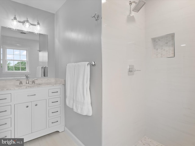 full bath featuring a tile shower and vanity