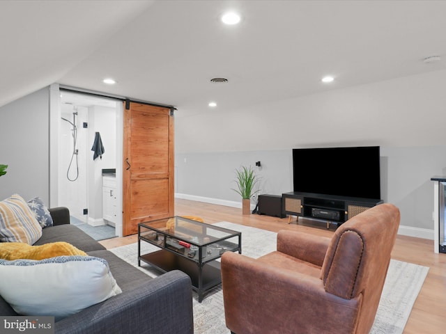 living area with a barn door, light wood-style floors, baseboards, lofted ceiling, and recessed lighting