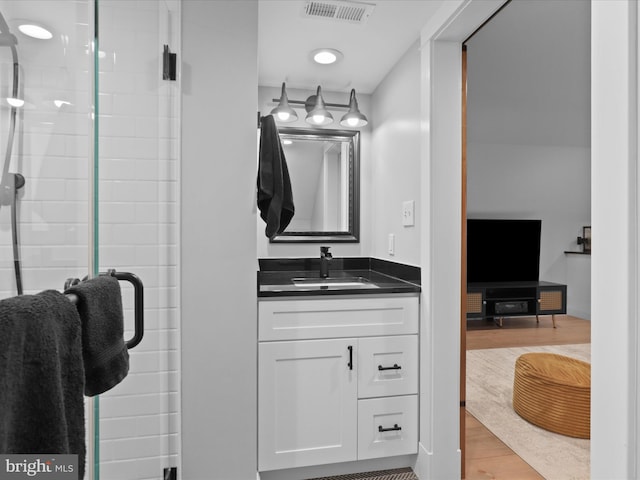 full bathroom featuring a stall shower, wood finished floors, and vanity