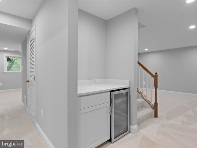 hall featuring wine cooler, light colored carpet, recessed lighting, stairs, and baseboards