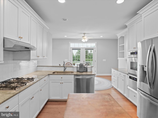 kitchen featuring stainless steel appliances, under cabinet range hood, a sink, ceiling fan, and light wood-style floors