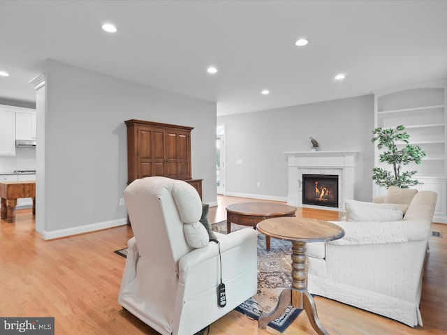 living area with light wood finished floors, recessed lighting, a fireplace, and baseboards