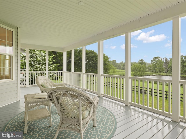 sunroom with a water view and view of scattered trees