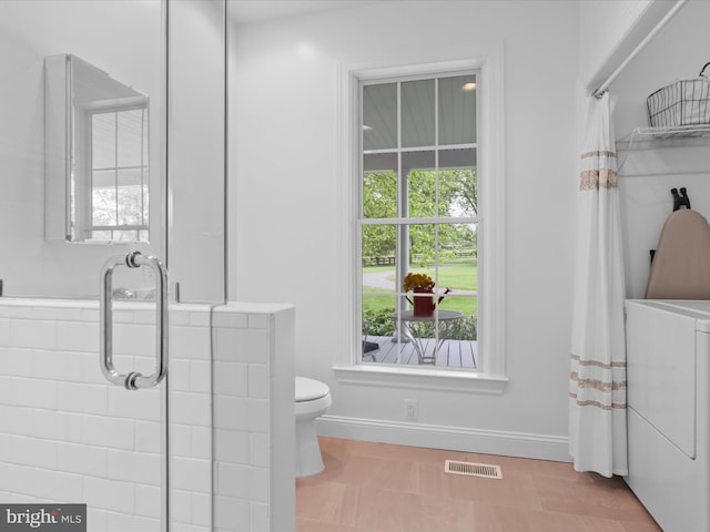 bathroom featuring toilet, curtained shower, baseboards, and washer and clothes dryer