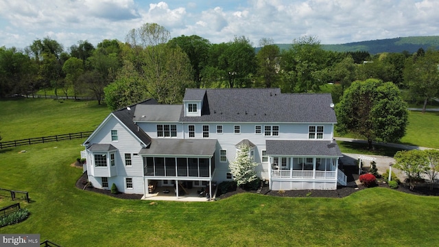 rear view of property featuring a sunroom and a shingled roof