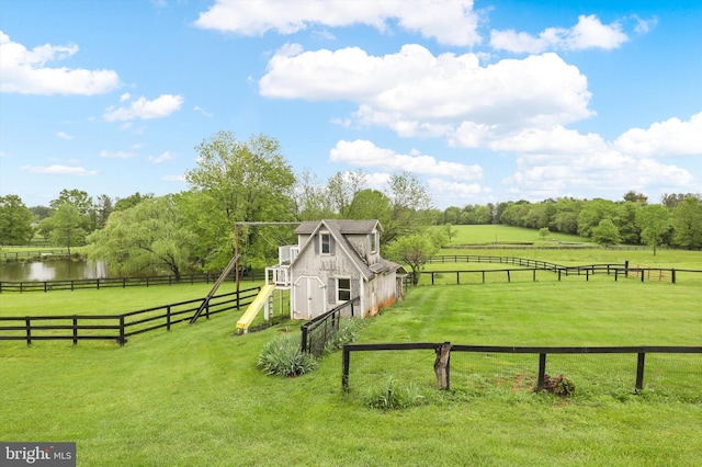 view of yard with a view of countryside, an outbuilding, and a water view