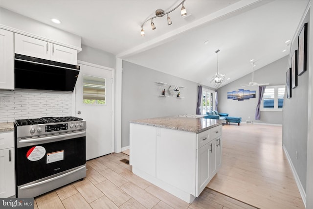 kitchen featuring stainless steel range with gas stovetop, extractor fan, decorative backsplash, open floor plan, and white cabinetry