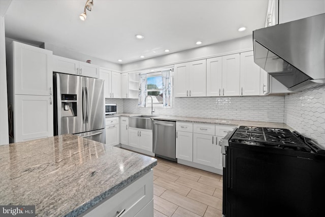 kitchen with stainless steel appliances, exhaust hood, a sink, light stone countertops, and recessed lighting