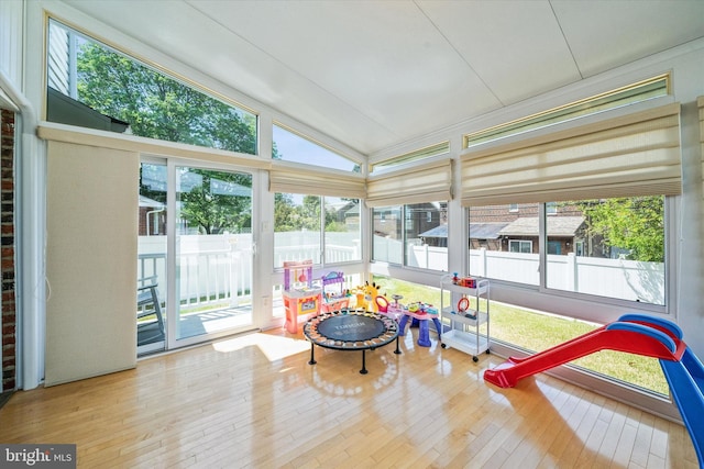 sunroom with healthy amount of natural light, vaulted ceiling, wood-type flooring, and a wooden deck