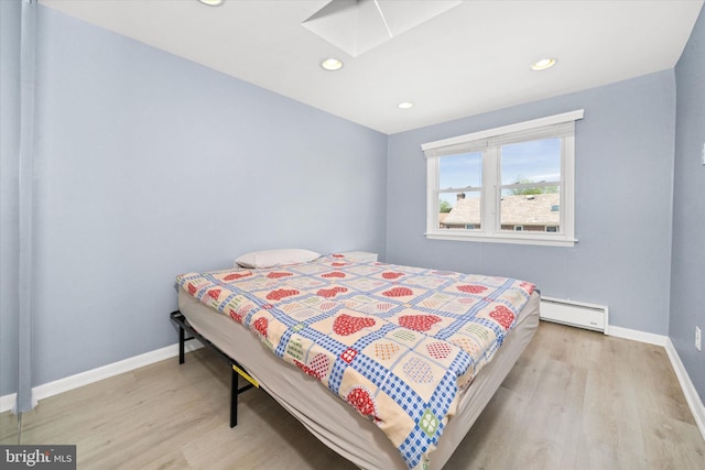 bedroom with a skylight, wood finished floors, baseboard heating, baseboards, and recessed lighting