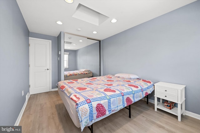 bedroom featuring wood finished floors, baseboards, a skylight, recessed lighting, and a closet