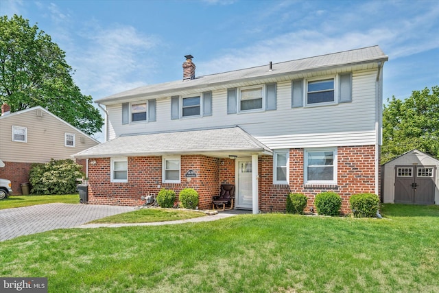 view of front of house featuring a storage unit, brick siding, an outdoor structure, a chimney, and a front yard