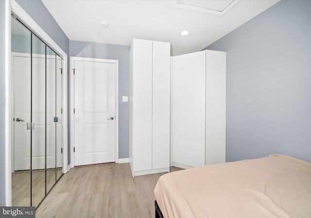 bedroom with light wood-type flooring, a closet, recessed lighting, baseboards, and attic access
