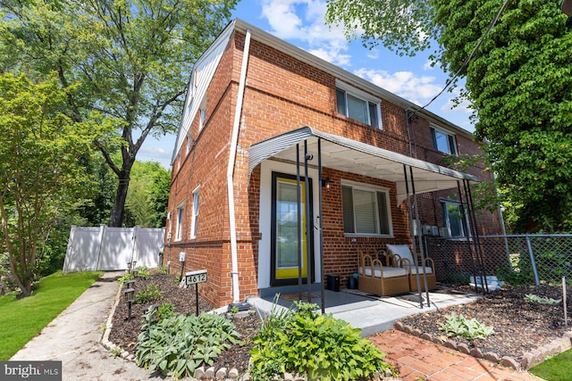 traditional-style home with brick siding, fence, driveway, and covered porch