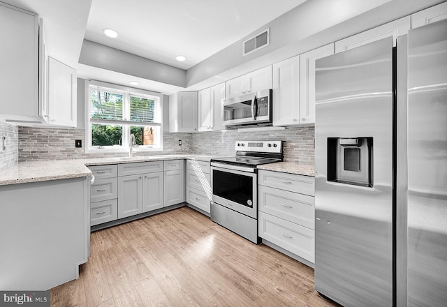4 Ingham Way, New Hope, PA 18938 - kitchen featuring appliances with stainless steel finishes, light wood-style floors, tasteful backsplash, light stone countertops, and a sink