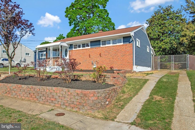 view of front of home featuring brick siding, fence, a gate, covered porch, and a chimney