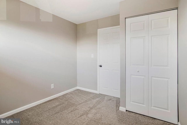 unfurnished bedroom featuring carpet floors, baseboards, and a closet