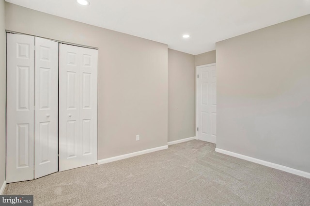 unfurnished bedroom featuring light carpet, baseboards, recessed lighting, and a closet