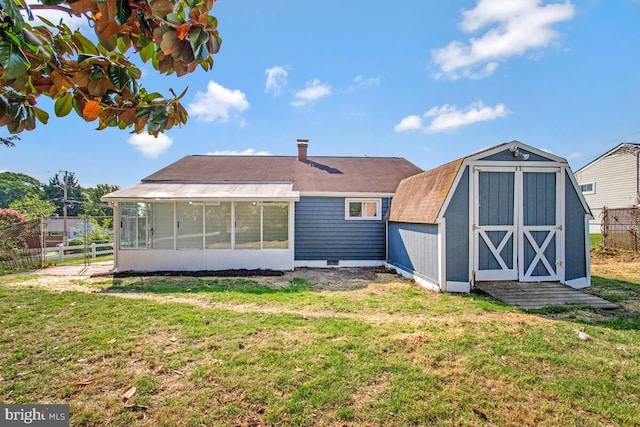 rear view of house with a sunroom, a shed, an outbuilding, and a shingled roof