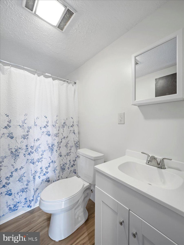 106 Monacan Trl, Hedgesville, WV 25427 - bathroom featuring wood finished floors, a textured ceiling, toilet, vanity, and a shower with shower curtain
