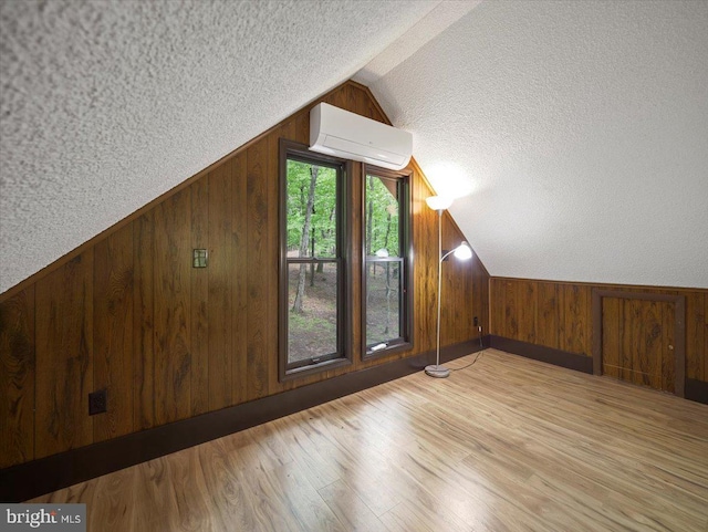 106 Monacan Trl, Hedgesville, WV 25427 - additional living space featuring a wall unit AC, a textured ceiling, vaulted ceiling, wood walls, and wood finished floors