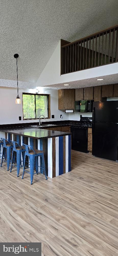 106 Monacan Trl, Hedgesville, WV 25427 - kitchen with black appliances, a textured ceiling, dark countertops, light wood finished floors, and decorative light fixtures