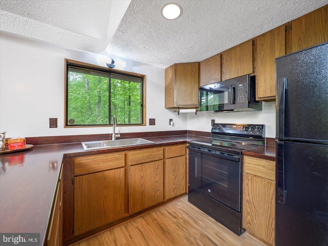 106 Monacan Trl, Hedgesville, WV 25427 - kitchen with black appliances, a sink, a textured ceiling, light wood finished floors, and dark countertops