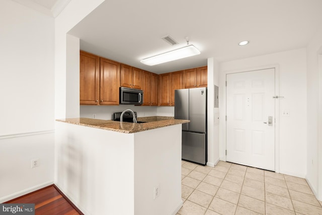 11710 Old Georgetown Rd Unit 1504, North Bethesda, MD 20852 - kitchen featuring stainless steel appliances, a peninsula, light stone countertops, recessed lighting, and brown cabinetry