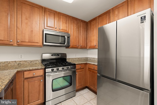 11710 Old Georgetown Rd Unit 1504, North Bethesda, MD 20852 - kitchen featuring appliances with stainless steel finishes, light tile patterned floors, brown cabinets, and light stone countertops