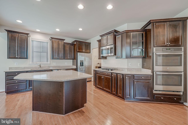 14762 Bell Tower Rd, Woodbridge, VA 22193 - kitchen with appliances with stainless steel finishes, light wood-type flooring, dark brown cabinetry, light stone counters, and a sink