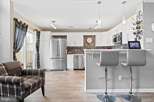 171 Timothy Cir, Wayne, PA 19087 - kitchen with stainless steel appliances, a kitchen bar, tasteful backsplash, light wood-style flooring, and white cabinetry