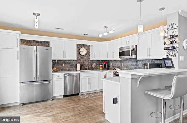 171 Timothy Cir, Wayne, PA 19087 - kitchen featuring stainless steel appliances, light countertops, white cabinets, a peninsula, and decorative backsplash