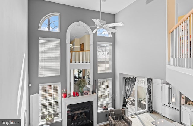 171 Timothy Cir, Wayne, PA 19087 - living area with ceiling fan, a high ceiling, a glass covered fireplace, and light wood-style floors