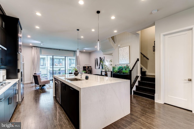 kitchen featuring a sink, dark wood finished floors, recessed lighting, an island with sink, and light stone countertops